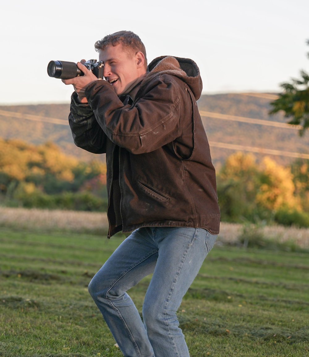 Nathanael Losch, owner of Territory Advertising, taking a photograph in a field at sunset
